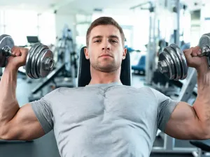 Kobieta na bieżni i mężczyzna na rowerku stacjonarnym w jasnej domowej siłowni, porównanie treningu cardio dla odchudzania.